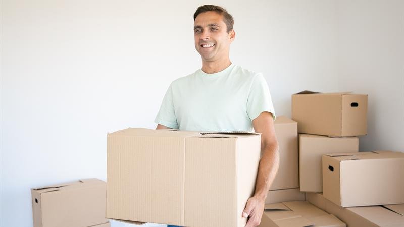 Hombre cargando una caja de cartón en una vivienda que se está vaciando